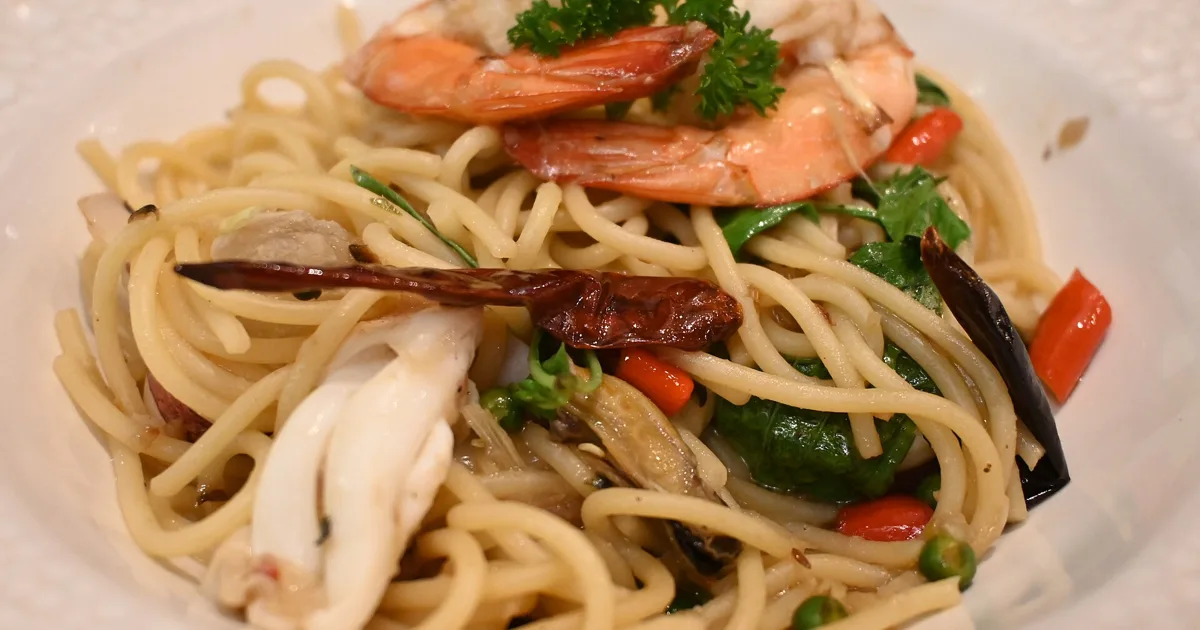 This is a mouthwatering plate of seafood pasta. The dish features spaghetti noodles tossed with various ingredients including plump shrimp,