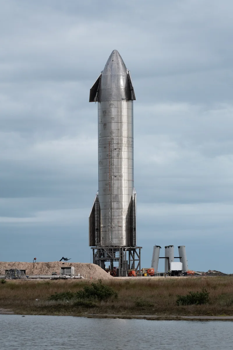 Starship SN9 sitting on its launch pad in Starbase. Its construction is more studier than prior prototypes, with a clean look. SN9's forward